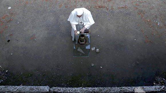El papa Francisco enciende una vela ante el “muro de la muerte”. Foto: EFE.