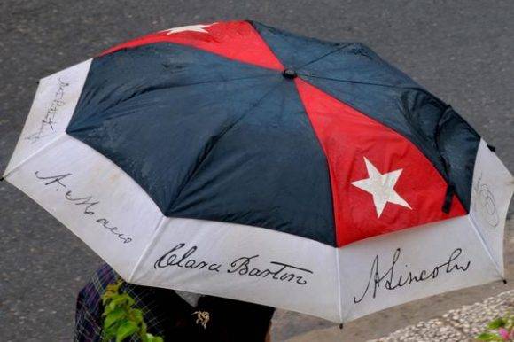 Persona protegiéndose de la lluvia al transitar por el Vedado, en La Habana, Cuba, el 30 de agosto de 2016.   Foto: Omara García Mederos / ACN