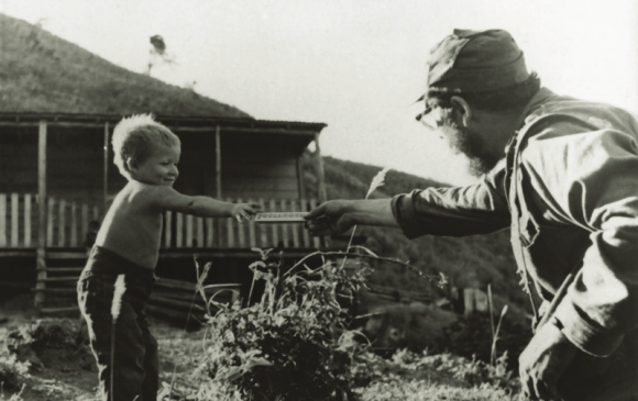 Fidel le ofrece una barra de chocolate a hijo de campesinos en la Sierra Maestra, 1958. Fuente: Oficina de Asuntos Históricos / Sitio Fidel Soldado de las Ideas.