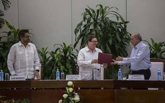 Cuba´s Foreign Minister Bruno Rodriguez, center, gives a copy of the peace accord to Humberto de La Calle, right, head of Colombia's government peace negotiation team, as Ivan Marquez, left, chief negotiator of the Revolutionary Armed Forces of Colombia (FARC), looks on after the signing of the latest and definitive text of the peace accord between the two sides in Havana, Cuba, Saturday, Nov. 12, 2016. (AP Photo/Desmond Boylan)