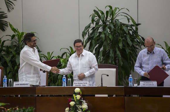 Ivan Marquez, chief negotiator of the Revolutionary Armed Forces of Colombia (FARC), left, shakes hands with Cuba´s Foreign Minister Bruno Rodriguez, center, as Humberto de La Calle, right, head of Colombia's government peace negotiation team stands on the right after the signing of the latest and definitive text of the peace accord between the two sides in Havana, Cuba, Saturday, Nov. 12, 2016. (AP Photo/Desmond Boylan)