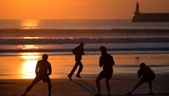A picture taken on January 24, 2017 shows people stretching at sunset on the beach of Les Sables d'Olonne, western France. / AFP PHOTO / JEAN-SEBASTIEN EVRARD