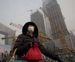 Una mujer que viste una mascarilla facial pasa por delante de una obra bajo la persistente smog que cubre Beijing, el 6 de enero de 2017. Foto: AP.