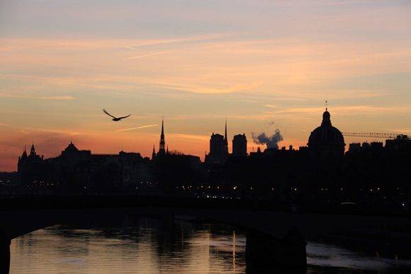 A picture taken on January 6, 2017 in Paris shows the sunrise above Notre Dame de Paris cathedral and the Institut de France. / AFP PHOTO / LUDOVIC MARIN