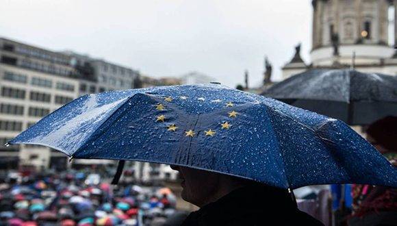 Un hombre sostiene un paraguas con la bandera de la UE durante las protestas. Foto: Filip Singer/ EFE.