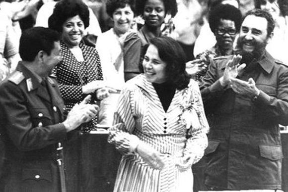 Fidel participa en la clausura del III Congreso de la Federación de Mujeres Cubanas, a su lado Vilma Espín Guillois, Secretaria de la FMC y el General de Ejército Raúl Castro Ruz, 8 de marzo de 1980. Foto tomada de Fidel Soldado de las Ideas.