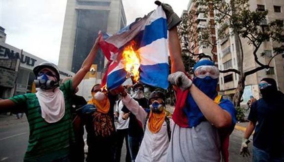 Miembros de la oposición venezolana queman una bandera cubana. Foto: AP.