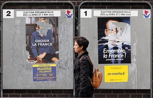 Algunos creen que estos políticos representan el cambio en Francia, otros consideran que la política gala seguirá desgastada no importa quién gane las elecciones. Una mujer camina cerca de carteles desgastados con el mensaje de Marine Le Pen (izq.) y Emmanuel Macron. Foto:  Getty Images. 