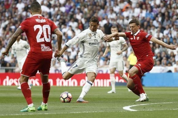 El delantero portugués del Real Madrid Cristiano Ronaldo (c) disputa un balón con el defensa portugués Daniel Carriço, del Sevilla, durante el partido de la trigésima séptima jornada de la Liga de Primera División en el estadio Santiago Bernabéu, en Madrid. Foto: EFE.