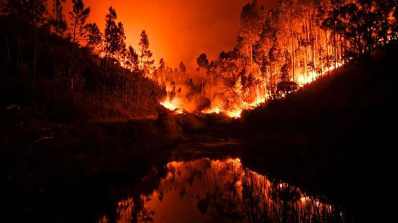 Las intensas llamas quedan reflejadas en una cañada en Penela, cerca de Coimbra Coimbra. Foto: AFP.