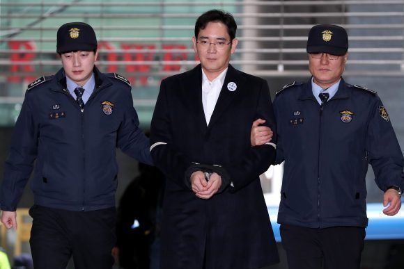 Jay Y. Lee, co-vice chairman of Samsung Electronics Co., center, is escorted by police officers as he arrives at the special prosecutors' office in Seoul, South Korea, on Sunday, Feb. 19, 2017. Lee was taken back to a special prosecutor's office for a second day following a second night in police custody as part of a corruption probe that has widened to include South Korea's largest industrial conglomerate. Photographer: SeongJoon Cho/Bloomberg via Getty Images