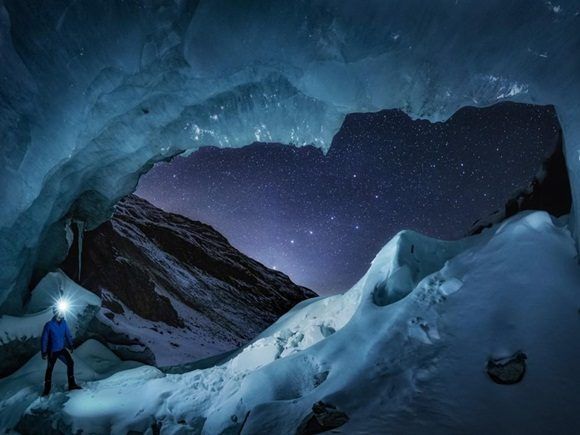 Un observador de estrellas contempla la constelación de la Osa Mayor perfectamente alineada con la ventana de la entrada a una gran cueva de glaciares en Engadin, Suiza.