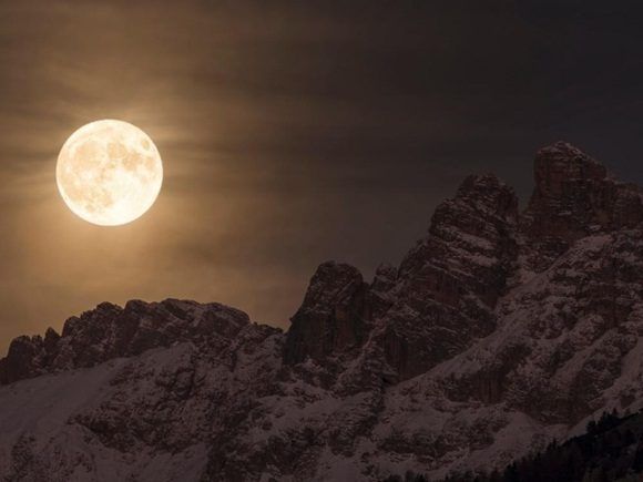 En esta imagen contemplamos una magnífica vista de la superluna iluminando el cielo nocturno, detrás de la montaña Marmarole, en el corazón de la cadena montañosa de los Dolomitas en Italia.