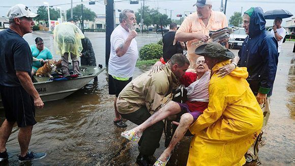 Unos vecinos usan su bote personal para rescatar a una señora llamada Jane Rhodes en Friendswood, Texas. Foto: Steve Gonzales/ Houston Chronicle.
