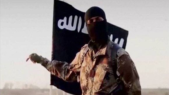 Un yihadista delante de la bandera del Estado Islámico, derrotado en Siria e Iraq. Foto: Reuters.