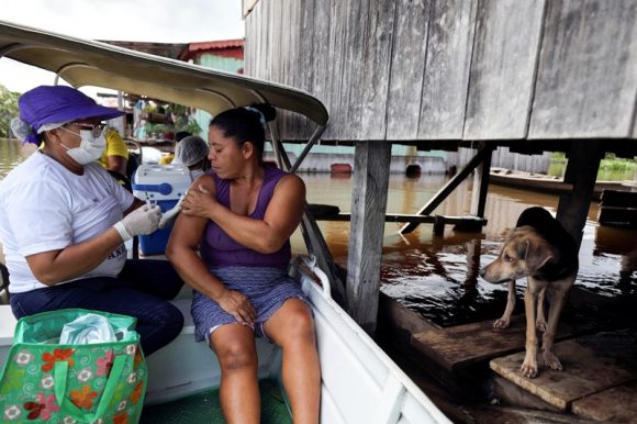 Un trabajador de la salud administra dosis de la vacuna Oxford AstraZeneca junto al río Amazonas en Brasil durante una inundación. Crédito Bruno Kelly Reuters Alamy