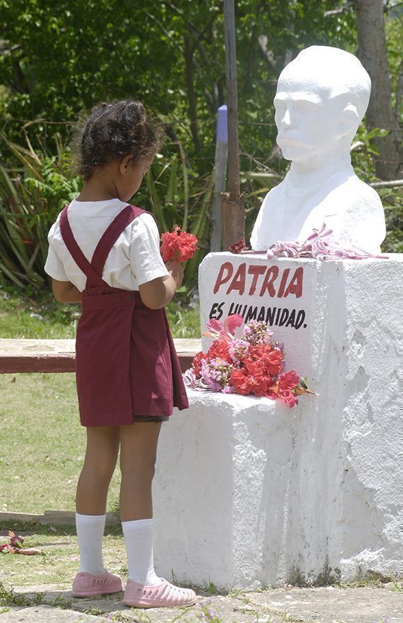 Pionera deposita una flor antes el busto de Jose Martí que se encuentra ubicado en la entrada de su escuela. Foto: Jorge Luis Sánchez Rivera/ Revista Bohemia.